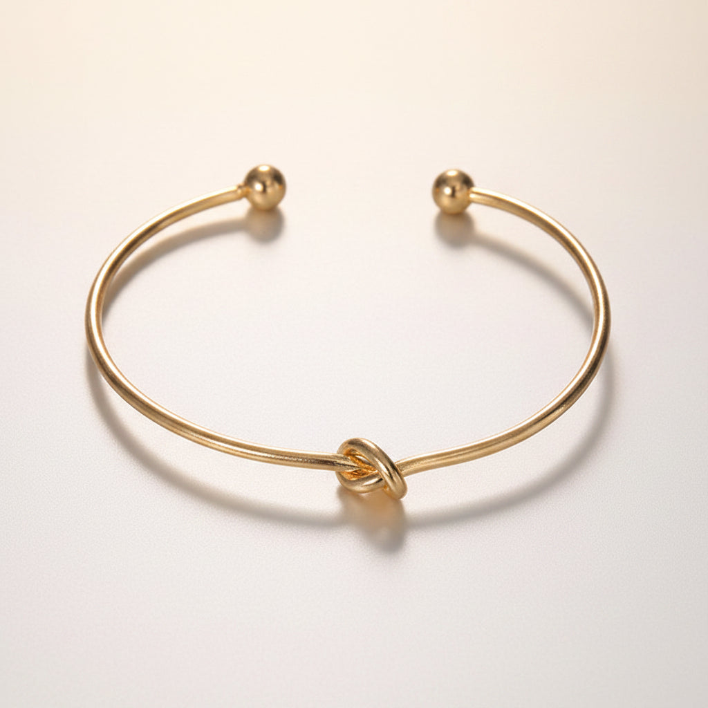 Gold bracelet with a knot design on a studio background