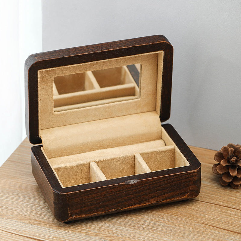 Wooden jewelry box with beige interior on a wooden surface