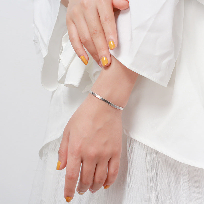 Silver bracelet on a wrist with a white background