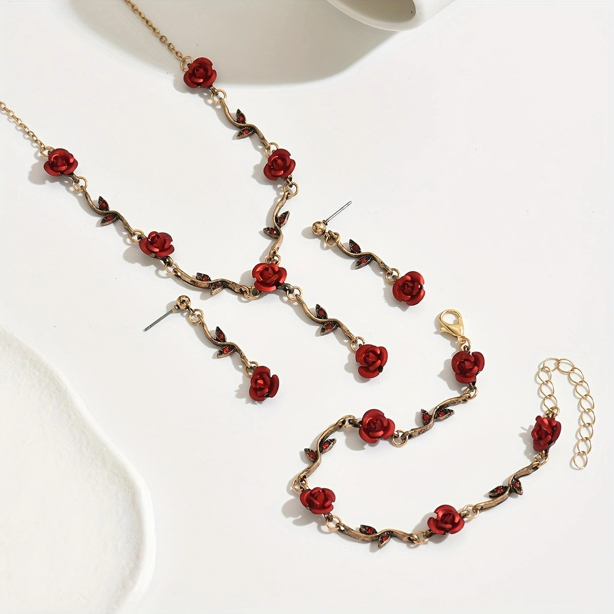 Jewelry set with red rose-themed necklace, earrings, and bracelet on a white background