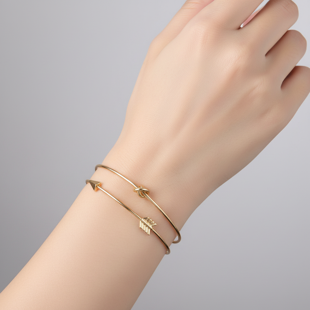 Gold bracelet on a wrist against a gray background