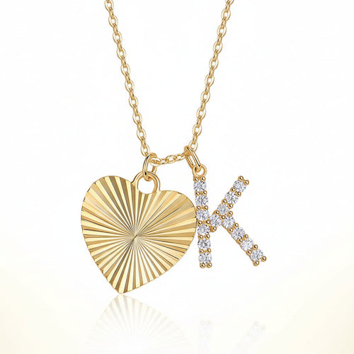 Gold necklace with a heart-shaped pendant and 'K' letter pendant on a white background