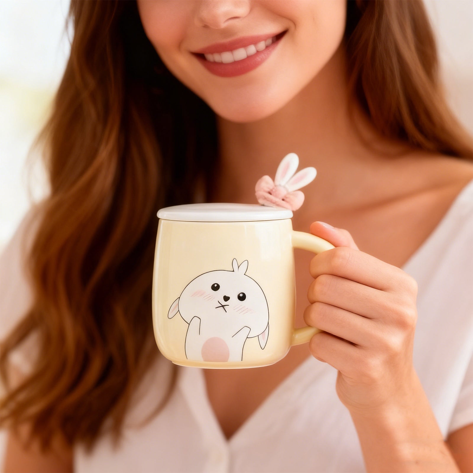 Woman holding a mug with a cartoon rabbit design and a pink bunny on top, smiling.
