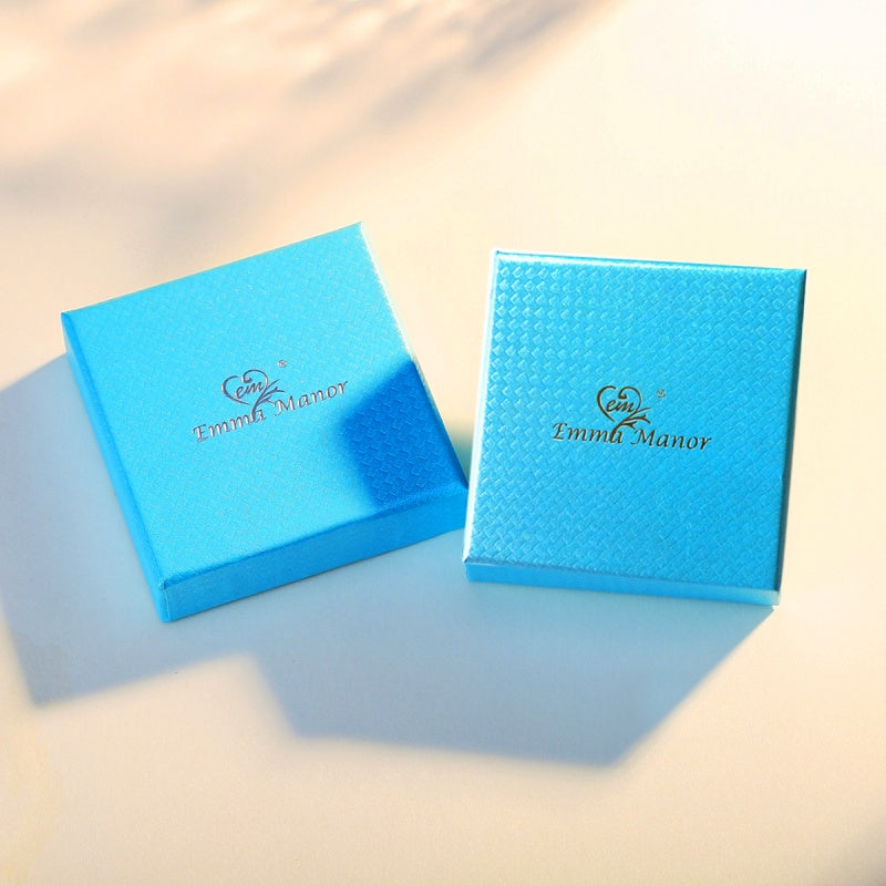 Two blue jewelry boxes with 'Emmi Manor' logo on a light background