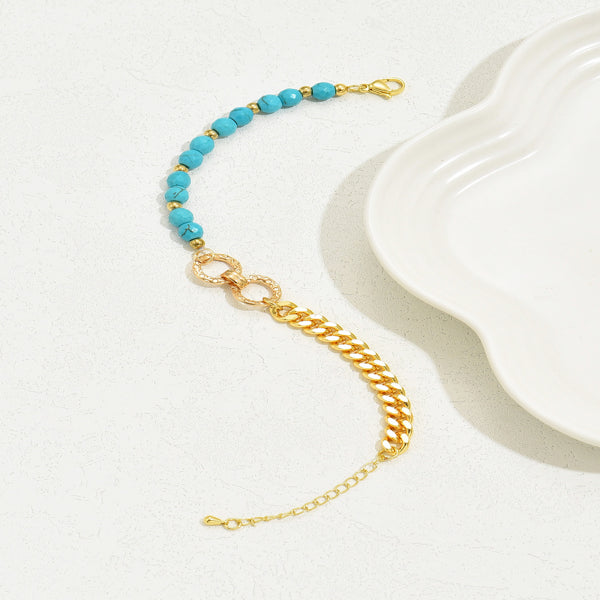 Gold chain bracelet with turquoise beads on a white surface