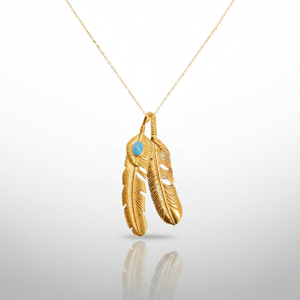 Gold feather pendant necklace with a blue gemstone on a white background
