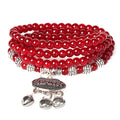 Red beaded bracelet with silver charm on a white background