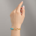 Bracelet with turquoise beads and gold chain on a white background