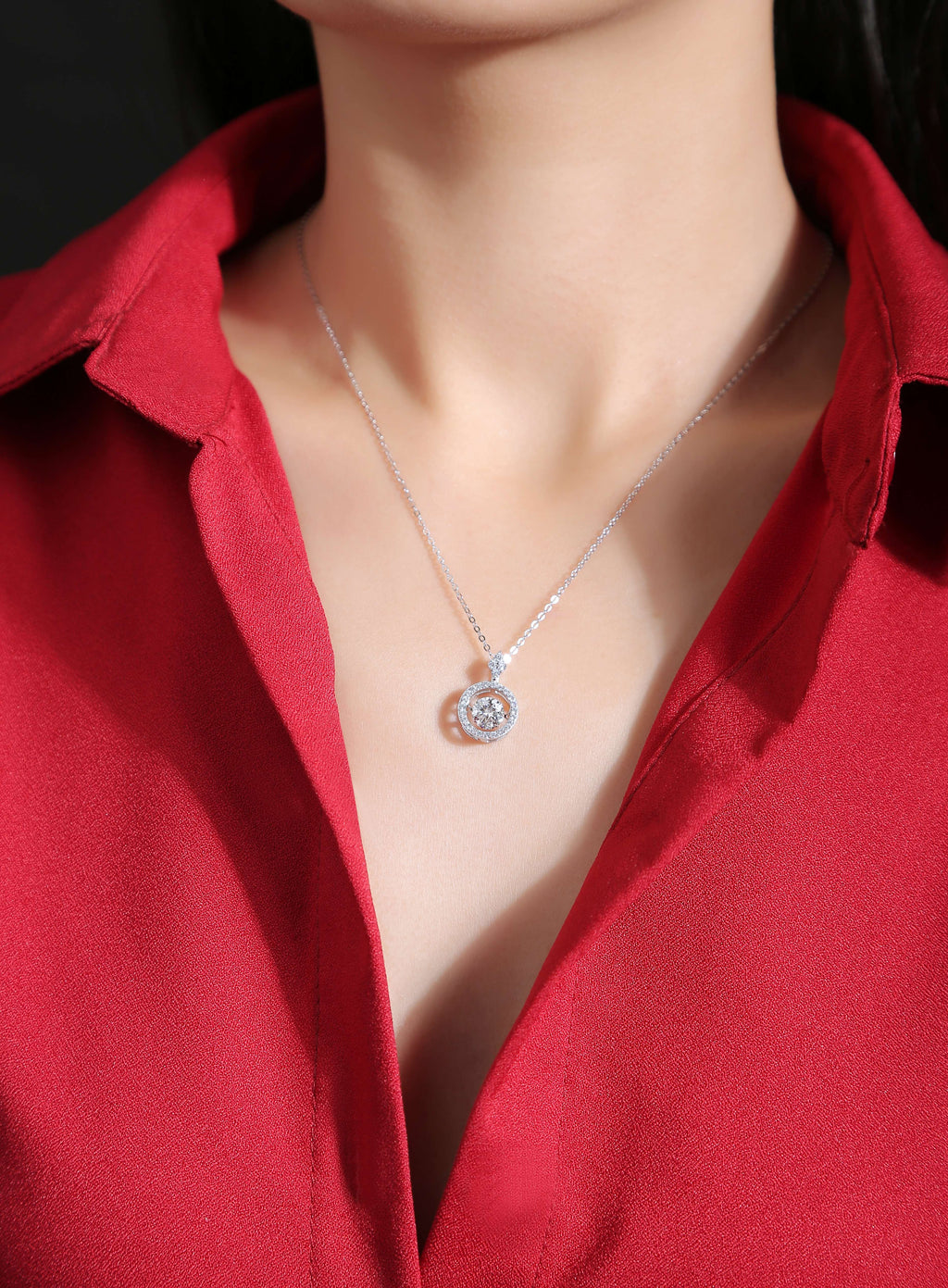 Silver necklace with a pendant worn by a person in a red shirt.