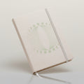 White notebook with decorative cover on a soft pink fabric background
